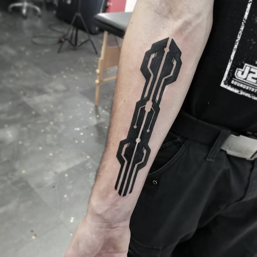 Minimalist cyberpunk tattoo on forearm featuring a bold, symmetrical geometric design in black ink